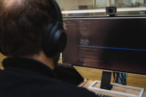 A person with headphones behind a computer screen working on software development.