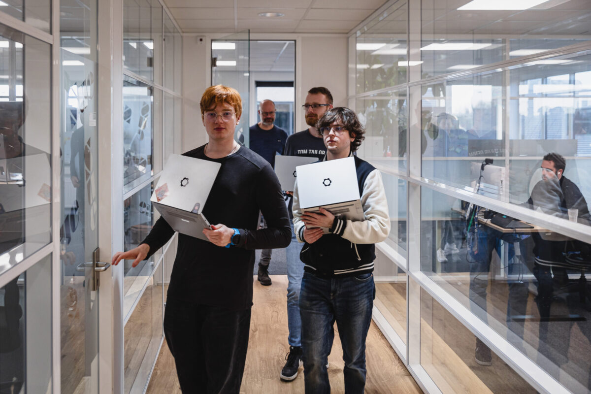 Data & AI customer case A group of people with laptops in their hands walking trough an office hallway.